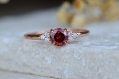 a close up of a ring with a red stone in the middle and diamonds around it