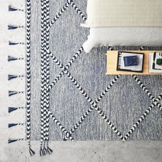 a blue and white rug with tassels on the floor next to a couch