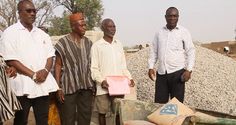 three men standing next to each other in front of piles of dirt and rocks with one man holding a pink object