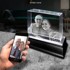 a person holding a cell phone in front of a glass block with an image on it