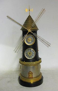 a small clock tower with two clocks on it's sides and windmills on top