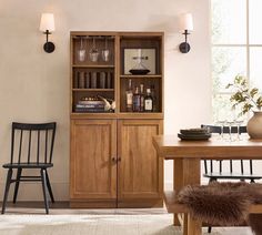 a dining room table and chairs in front of a bookcase with wine glasses on it