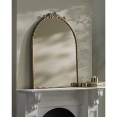 a white fireplace with a mirror above it