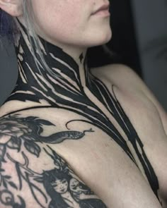 a woman with tattoos on her chest and neck