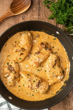 a skillet filled with chicken and gravy on top of a wooden table