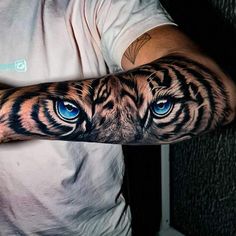 a man's arm with blue eyes and a tiger tattoo on the left arm