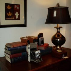 a lamp and some books on a table with a cell phone in front of it