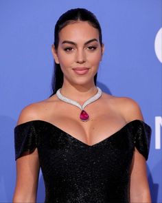 a woman in a black dress with a red stone necklace on her neck and shoulder