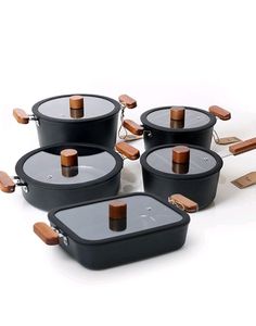 four black pots and pans with wooden handles