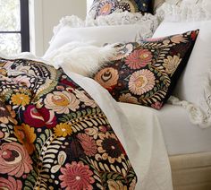 the comforter is made up with colorful flowers and feathers on it's bed