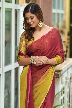 a woman in a red and yellow sari standing next to a window with her hands on her hips