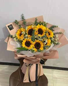 a bouquet of sunflowers is wrapped in brown paper and tied with a ribbon