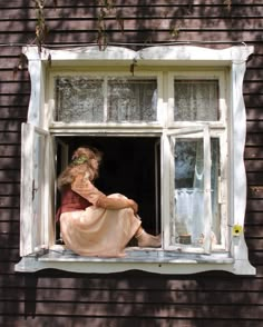 a woman sitting on the window sill looking out