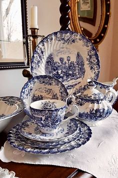 a blue and white china set on top of a wooden table