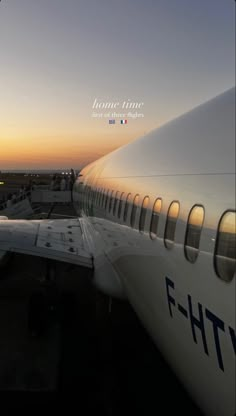 an airplane is sitting on the tarmac at sunset with its wing down and it's lights on