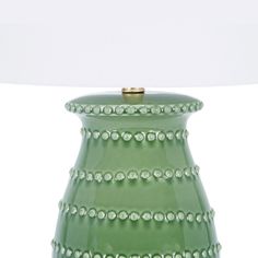 a green vase sitting on top of a table next to a white lamp with a white shade