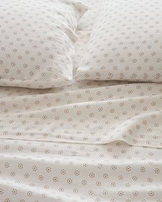 an unmade bed with white sheets and polka dot print on the comforter is shown