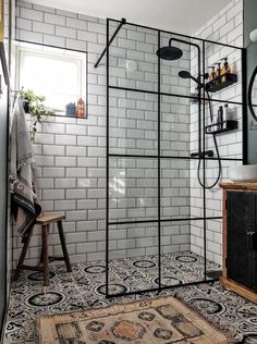 a bathroom with black and white tiles on the floor, shower head, mirror, rug and sink