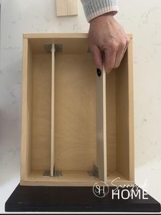 Woman placed drawer divider between brackets to organize bathroom cabinet drawer.