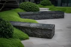 a stone bench sitting in the middle of a garden with grass growing on top of it