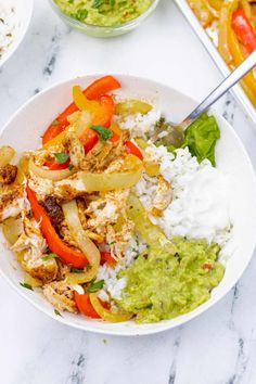 a white plate topped with chicken and veggies next to rice