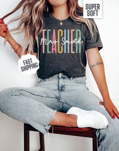 You'll adore this personalized teacher shirt! This Bella Canvas tee combines ultimate comfort with a charming design for your elementary, middle or high school teacher. The front features a vibrant design with "Teacher" in bold block letters and a stylish script font overlay of your personalized teacher's name. Available in four beautiful colors, it's the ideal gift for your child's teacher for Christmas, a birthday, or even a treat for yourself. Plus, it's a wonderful teacher appreciation gift. Personalized Short Sleeve T-shirt For Back To School, Personalized Casual Tops For Teacher Appreciation, Personalized School Spirit T-shirt With Crew Neck, Personalized Crew Neck Tops For Back To School, Personalized Tops For Back To School With School Spirit, Personalized Tops With School Spirit For Back To School, Short Sleeve T-shirt With Name Print For Teacher Appreciation, Personalized Tops For Back To School, School Spirit T-shirt With Name Print For Teacher Appreciation