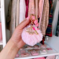 a hand holding a pink pom - pom keychain with the word love on it