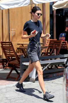 a woman in black shirt and shorts walking down street