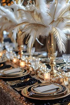 the table is set with black and gold plates, silver place settings, and white feather centerpieces