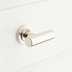 a close up of a door handle on a white cabinet