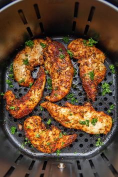 some chicken is cooking in an air fryer with parsley on the top and sides