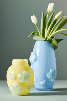 two vases with flowers in them sitting on a table