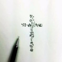 a drawing of a cross with flowers on it and a pen in the foreground