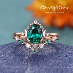 an emerald and diamond ring on top of a blue rock with flowers in the background