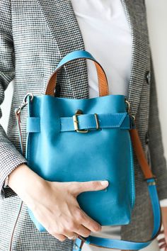 a woman holding a blue handbag in her right hand with the words turquise on it