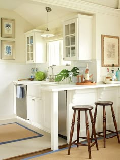 a white kitchen with two stools in front of the sink and dishwasher