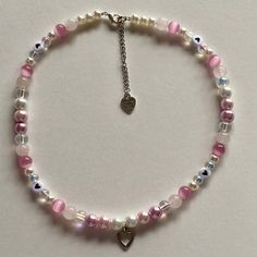 a pink and white beaded bracelet with a heart charm hanging from it's end