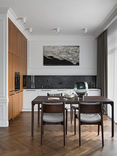 a dining room table with chairs and a painting on the wall