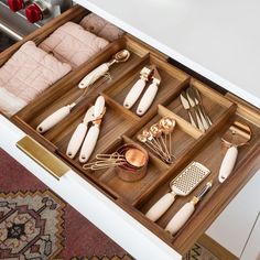 an open drawer with utensils and other items in it on top of a rug