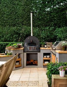 an outdoor kitchen with potted plants on the counter and wood burning oven in the center