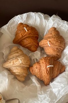 three croissants and two other pastries on a white paper wrapper