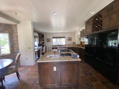 a large kitchen with an island in the middle and tile flooring on the other side