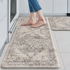 a woman standing on top of a rug in the middle of a kitchen with white cabinets