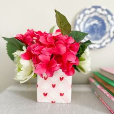 a vase filled with red and white flowers on top of a table next to books