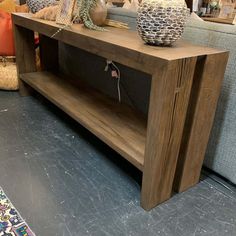 a wooden table sitting on top of a floor next to couches and tables with vases