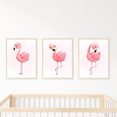 three pink flamingos are hanging on the wall next to a crib