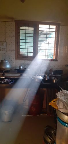 sunlight shining through the window in a kitchen with pots and pans on the counter