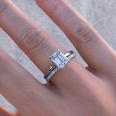 a woman's hand with a ring on it and an engagement ring in the middle