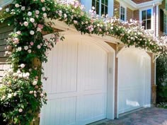 a white garage with flowers growing over it