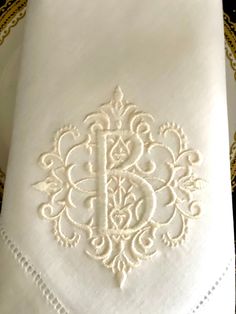 a white napkin with an ornate design on it sitting on a gold plated tray